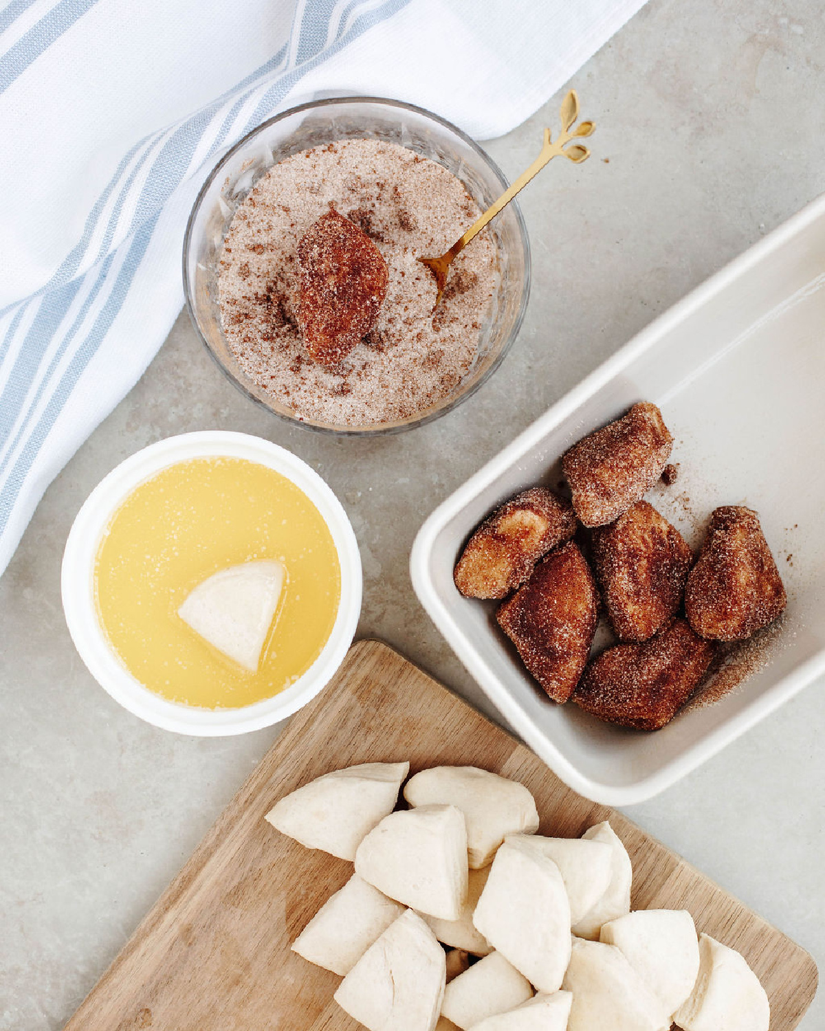 Biscuit pieces dipped in melted butter and cinnamon sugar before placing into a white loaf pan to bake.