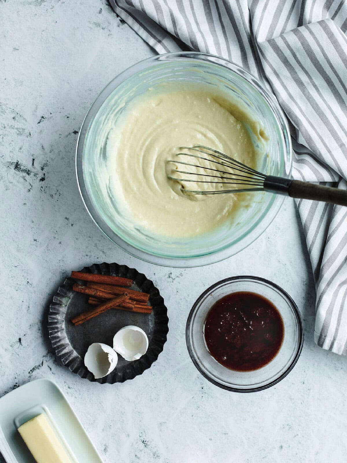 Batter in a glass mixing bowl and cinnamon mixture in a small bowl ready to combine.