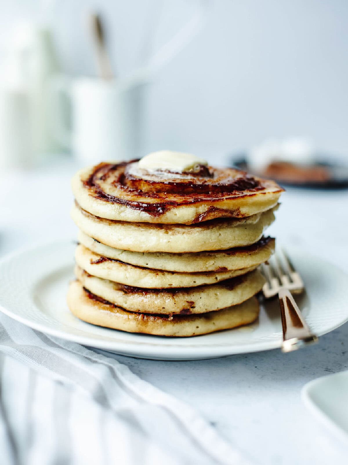 A stack of 6 cinnamon swirl pancakes on a white plate.