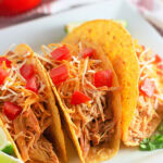 A white plate with three crunchy tacos filled with Ranch seasoned chicken from the slow crockpot.