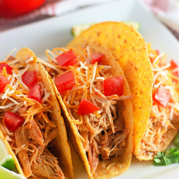 A white plate with three crunchy tacos filled with Ranch seasoned chicken from the slow crockpot.