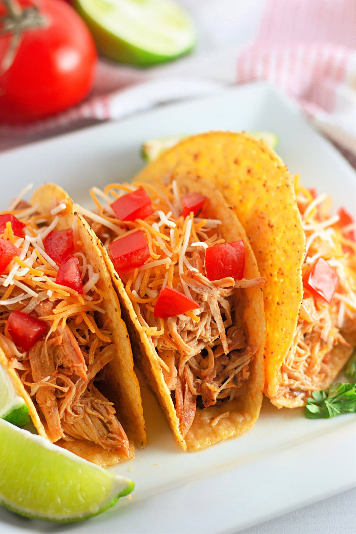 A white plate with three crunchy tacos filled with Ranch seasoned chicken from the slow crockpot.