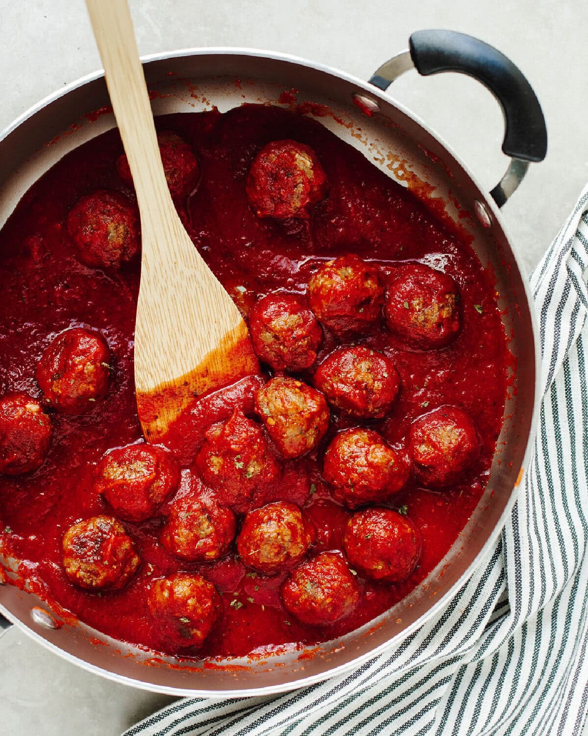 Homemade meatballs in marinara sauce cooking in a skillet.