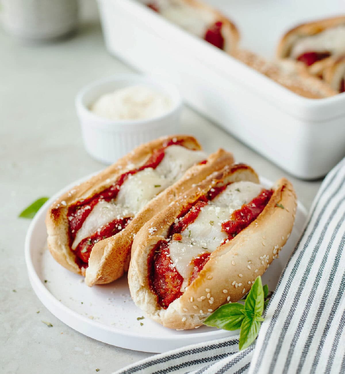 Two meatball subs on a white plate ready to serve.