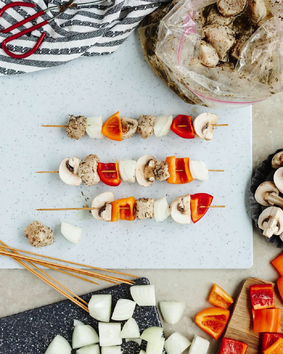 Marinated chicken pieces plated on a wood skewer with mushrooms, peppers, and onions.