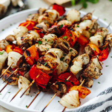 Marinated chicken kabobs grilled and placed on a white serving platter.