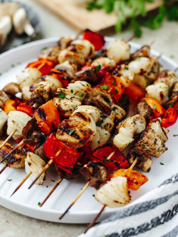 Marinated chicken kabobs grilled and placed on a white serving platter.