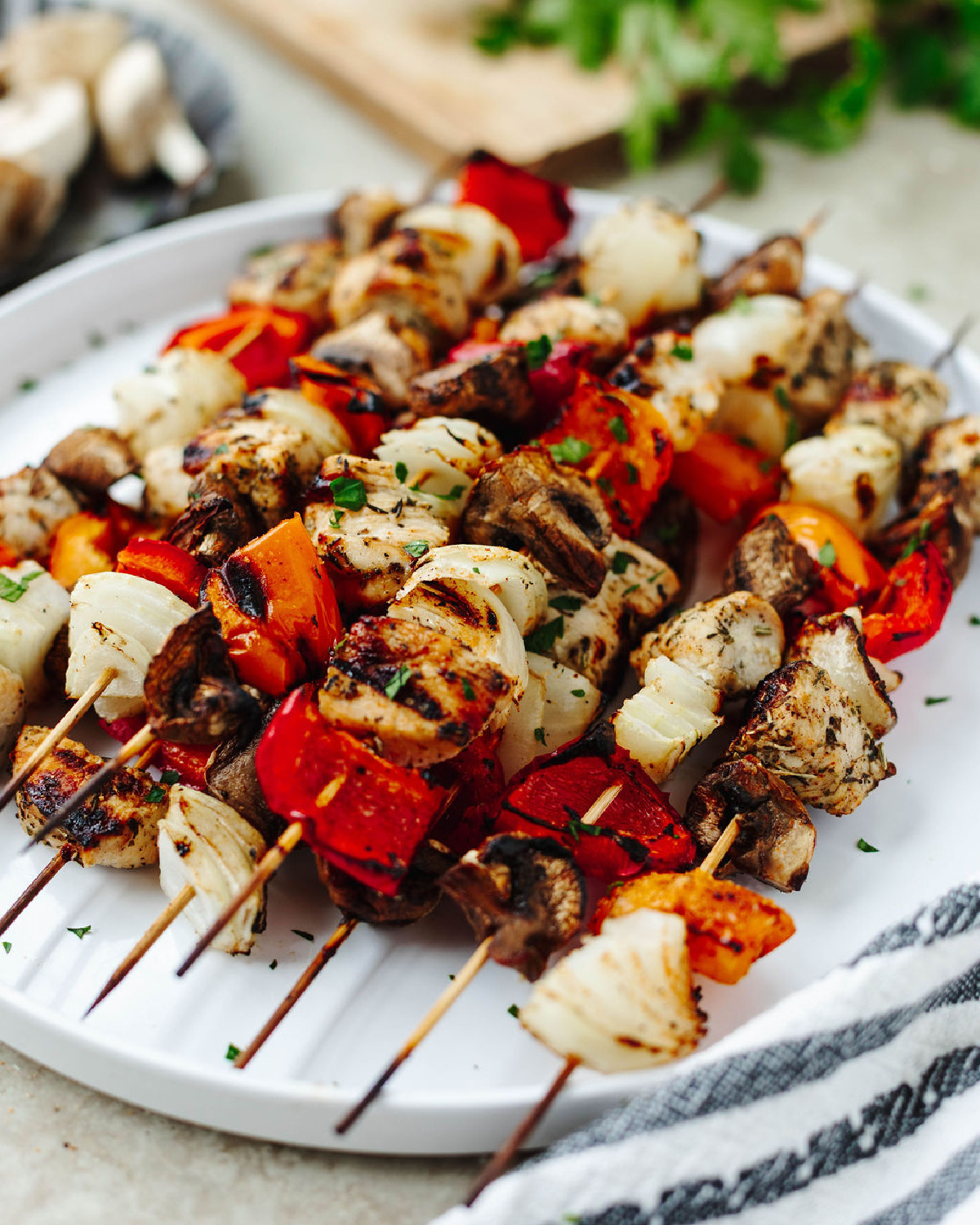 Marinated chicken kabobs grilled and placed on a white serving platter.