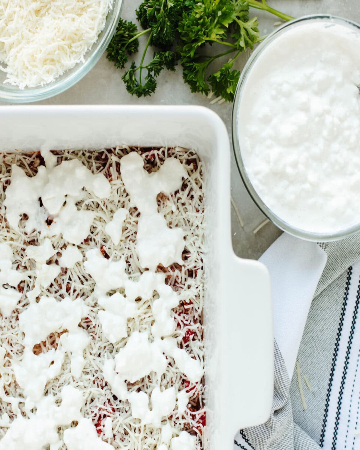 Cottage cheese spread over a layer of mozzarella while assembling homemade lasagna.