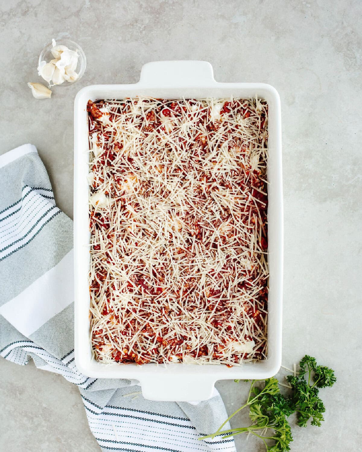 Unbaked lasagna layered with meat sauce, mozzarella, and Parmesan cheese before baking.