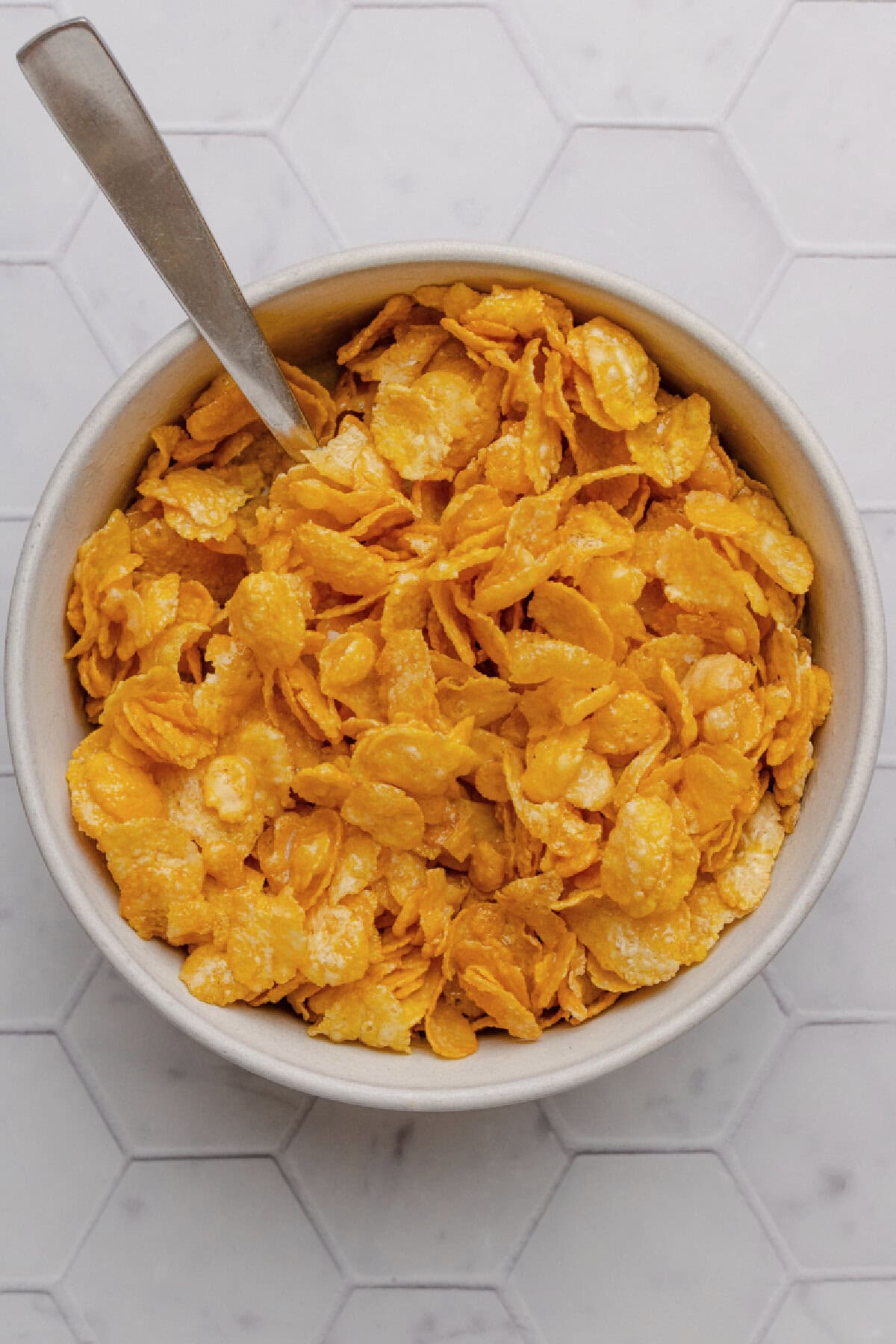 Cornflakes combined with melted butter in a small bowl.