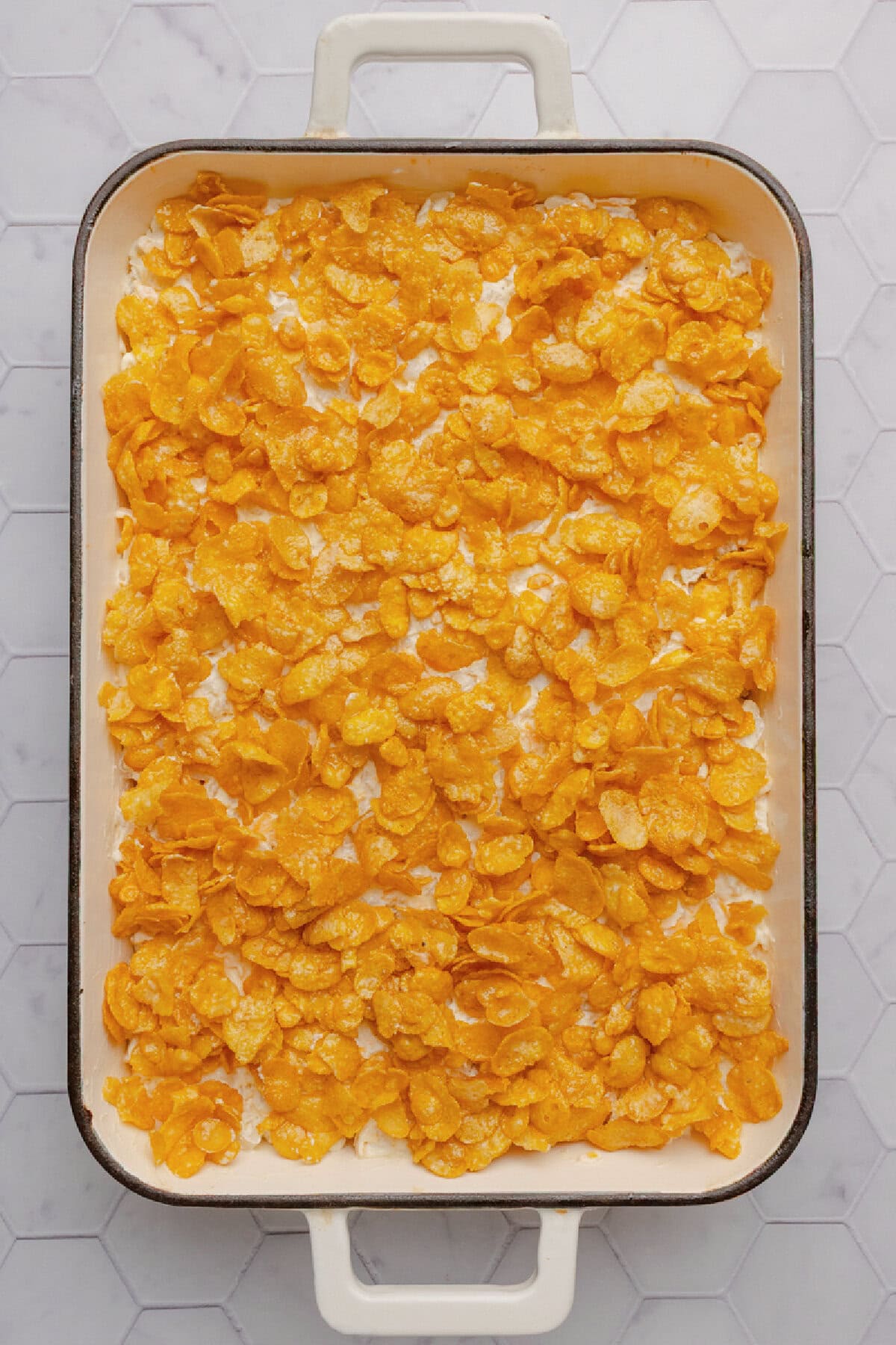 Crunchy cornflakes on top of a potato casserole in a baking dish.