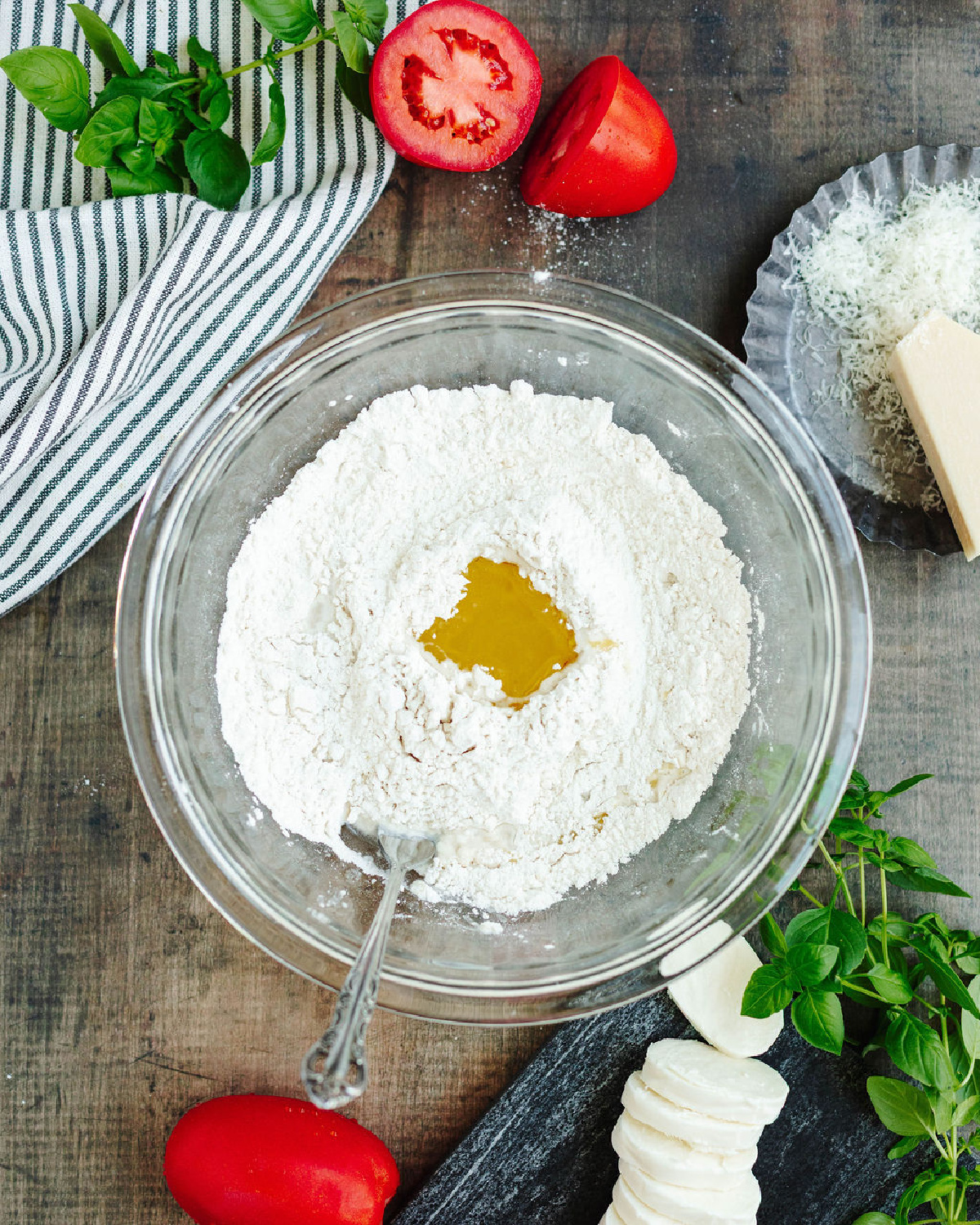 Flour, olive oil, baking powder and salt added in a glass mixing bowl.