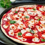 Baked pizza with tomato sauce, tomatoes, and basil.