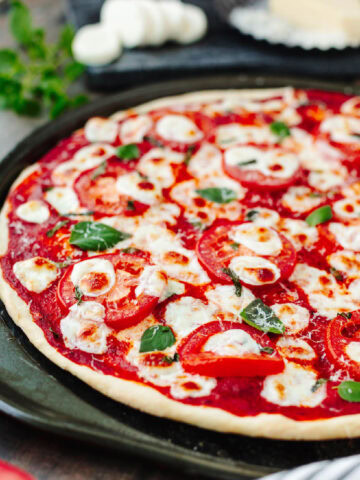 Baked pizza with tomato sauce, tomatoes, and basil.