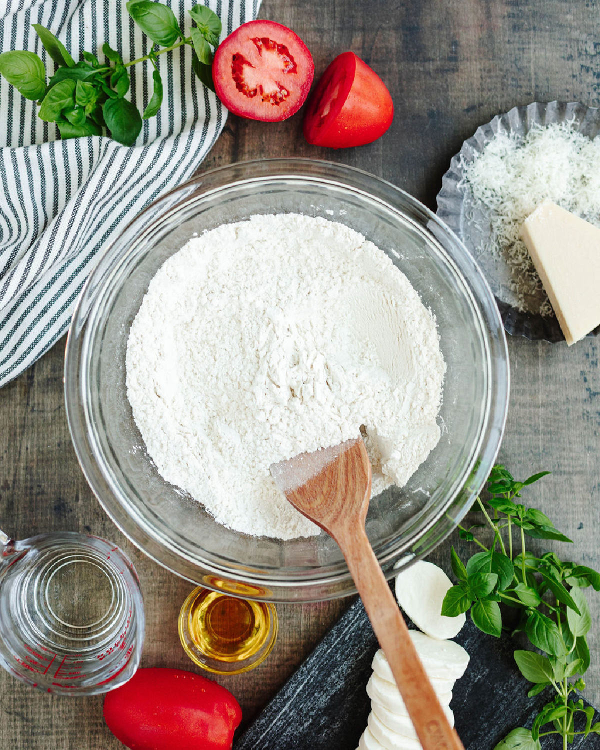 Flour, baking powder, and salt combined in a mixing bowl using a wooden spoon.