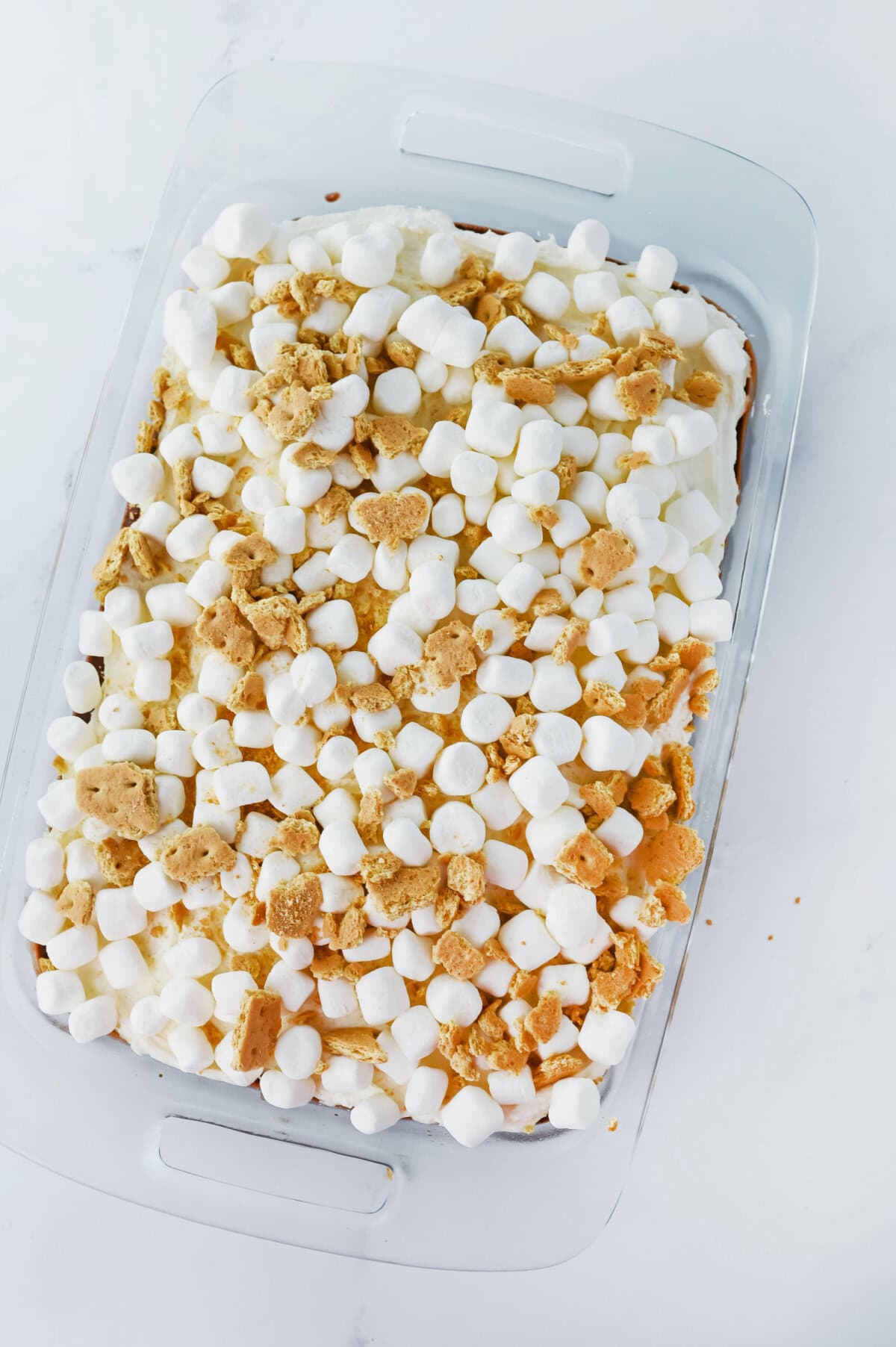 Broken up graham crackers and mini marshmallows on top of a chocolate cake.