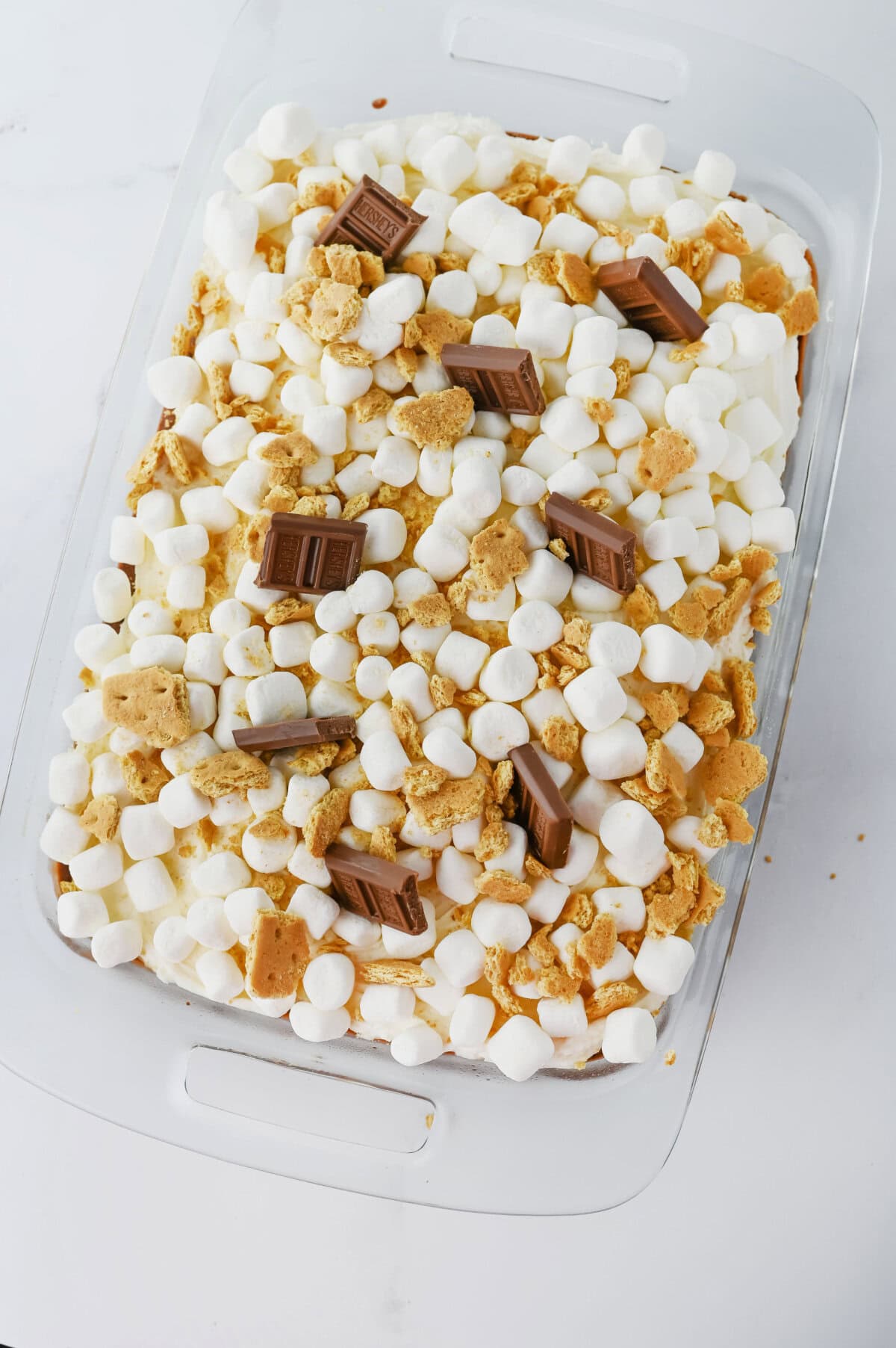 A smores poke cake in a 9x13 baking pan ready to serve.