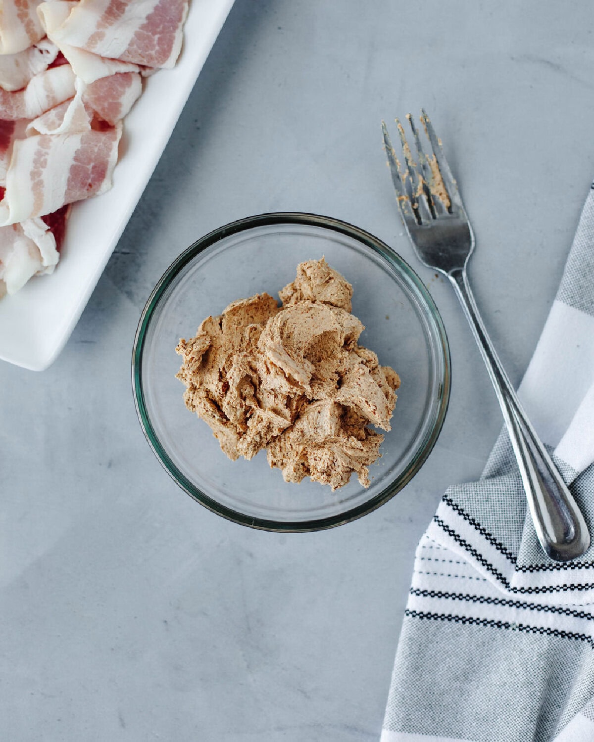 Chipotle pepper and goat cheese combined in a glass mixing bowl using a fork.