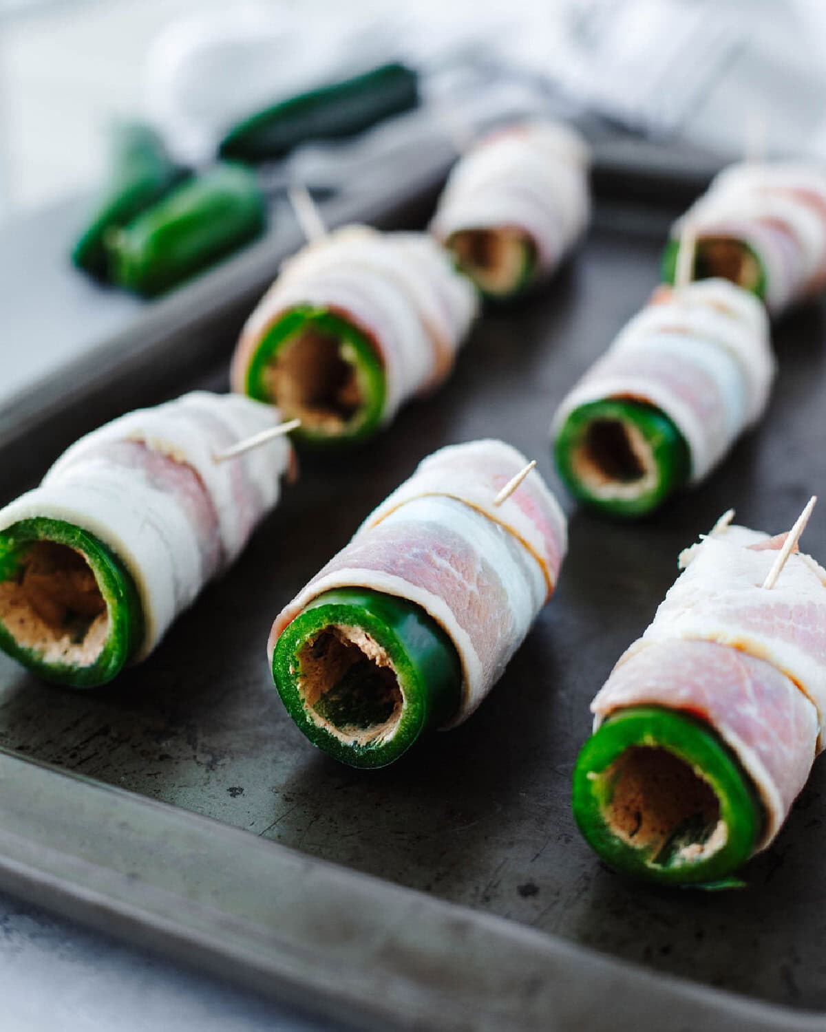 A slice of bacon wrapped around a hollowed out jalapeno.
