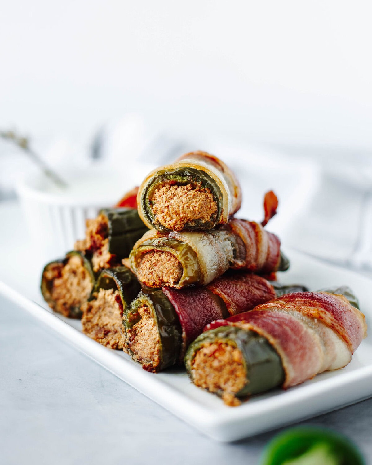 Stuffed jalapenos stacked on a white plate.