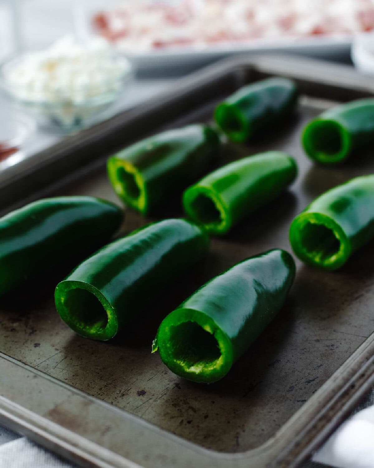 Fresh jalapenos that have been hollowed out and placed on a cookie sheet.