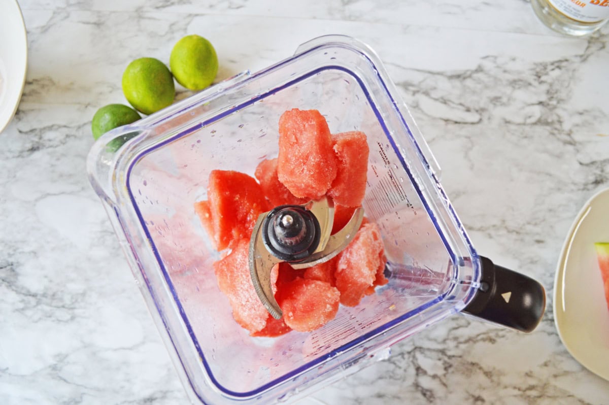 Fresh watermelon chunks added to a blender.