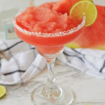 A watermelon margarita salt rimmed with a lime wedge and watermelon wedge.