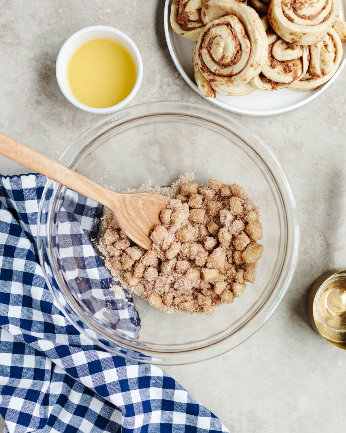 Diced apple chunks tossed in cinnamon sugar in a glass mixing bowl with a wooden spoon.