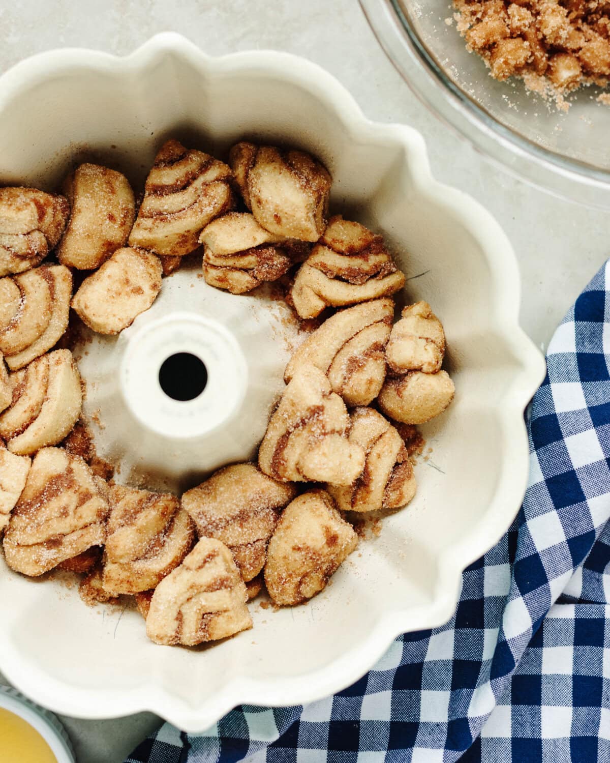 Sliced cinnamon roll pieces covered in cinnamon sugar and layered in a bundt pan.