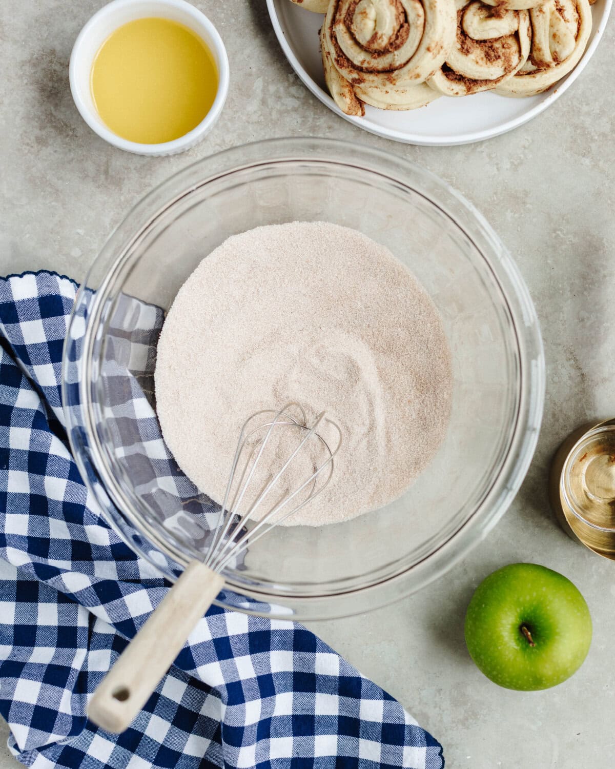 Cinnamon and sugar combined with a whisk in a glass mixing bowl.
