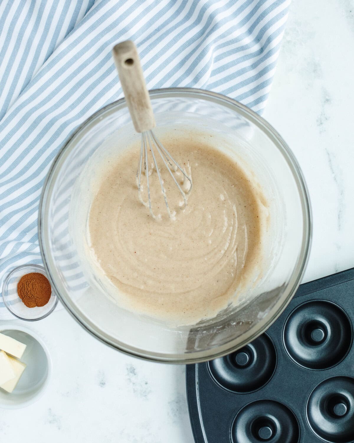 Wet ingredients added to a dry mixture to form a batter in a glass mixing bowl.