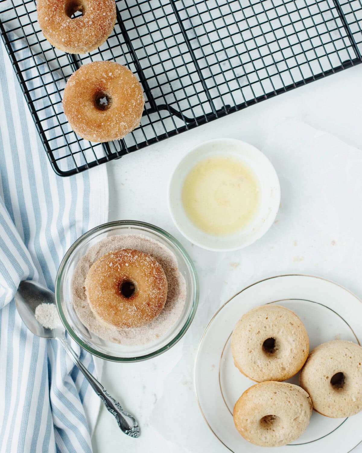 Coating baked donuts in cinnamon sugar after dipping in melted butter.