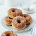 Baked cinnamon sugar donuts on a white plate.