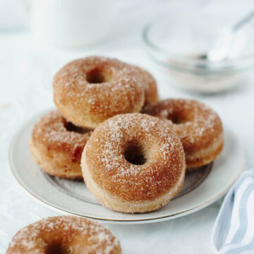 Baked cinnamon sugar donuts on a white plate.
