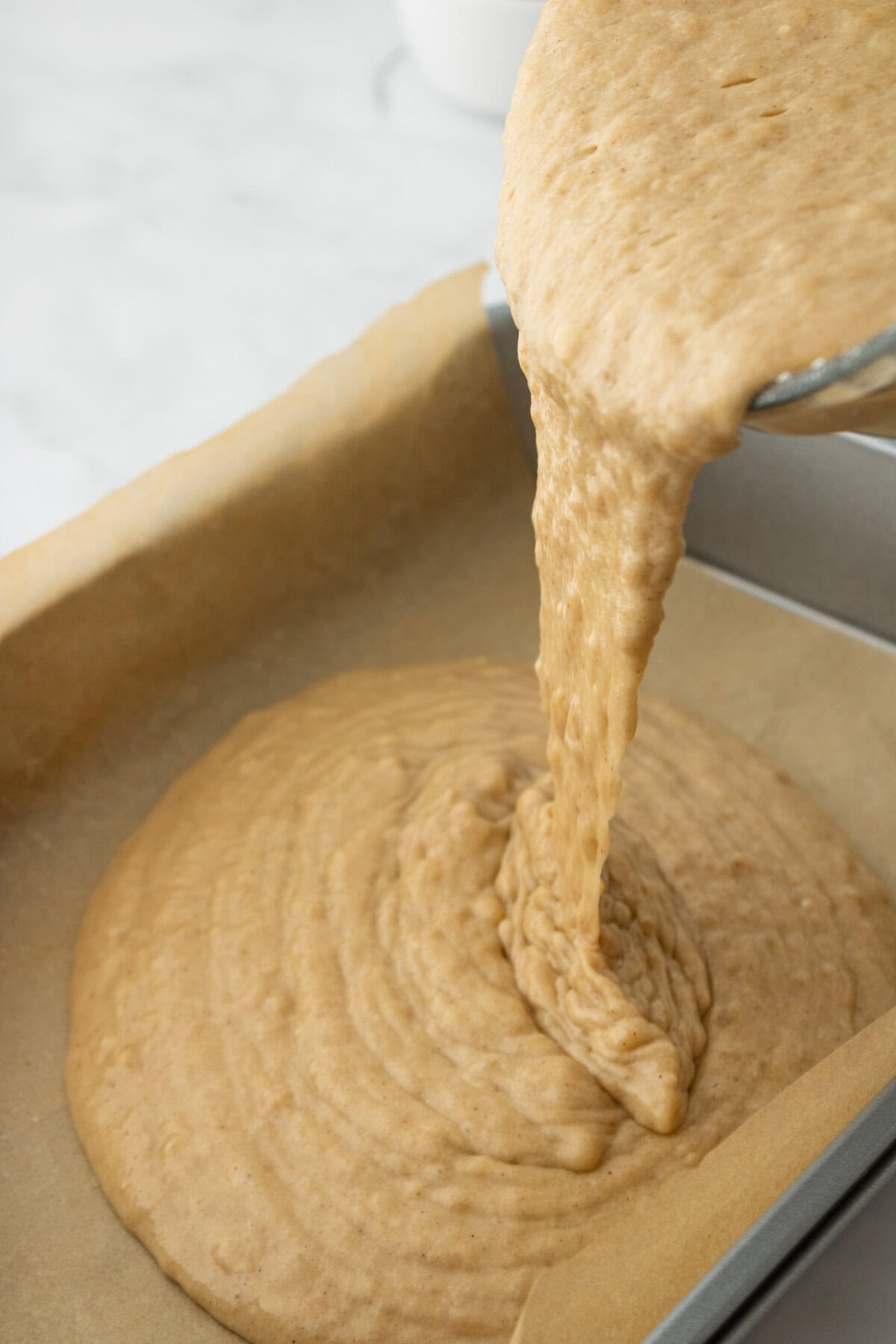 Banana bread batter spread into a prepared baking pan.