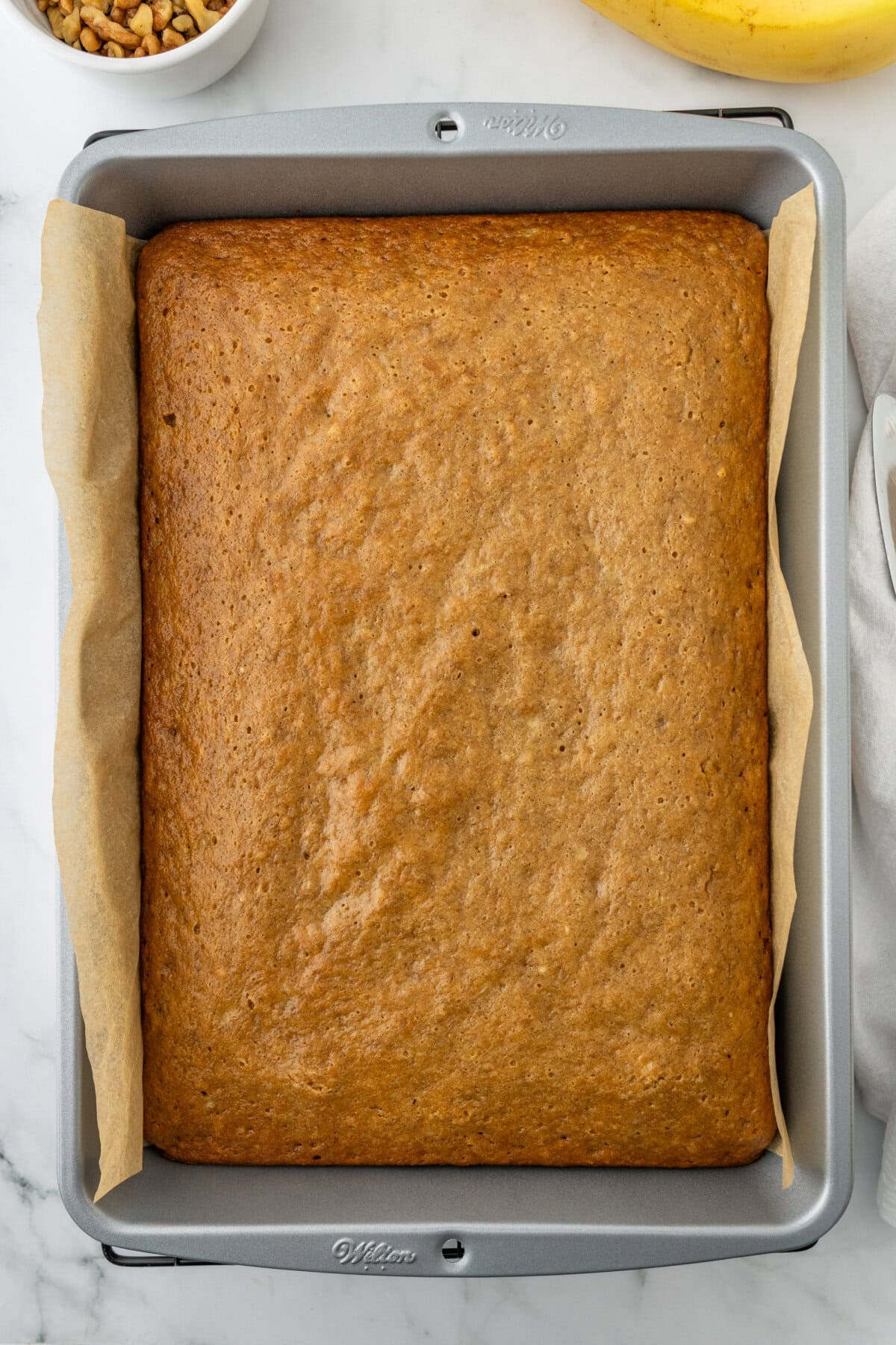 Banana bars baked in a 9x13 baking pan lined with parchment paper.