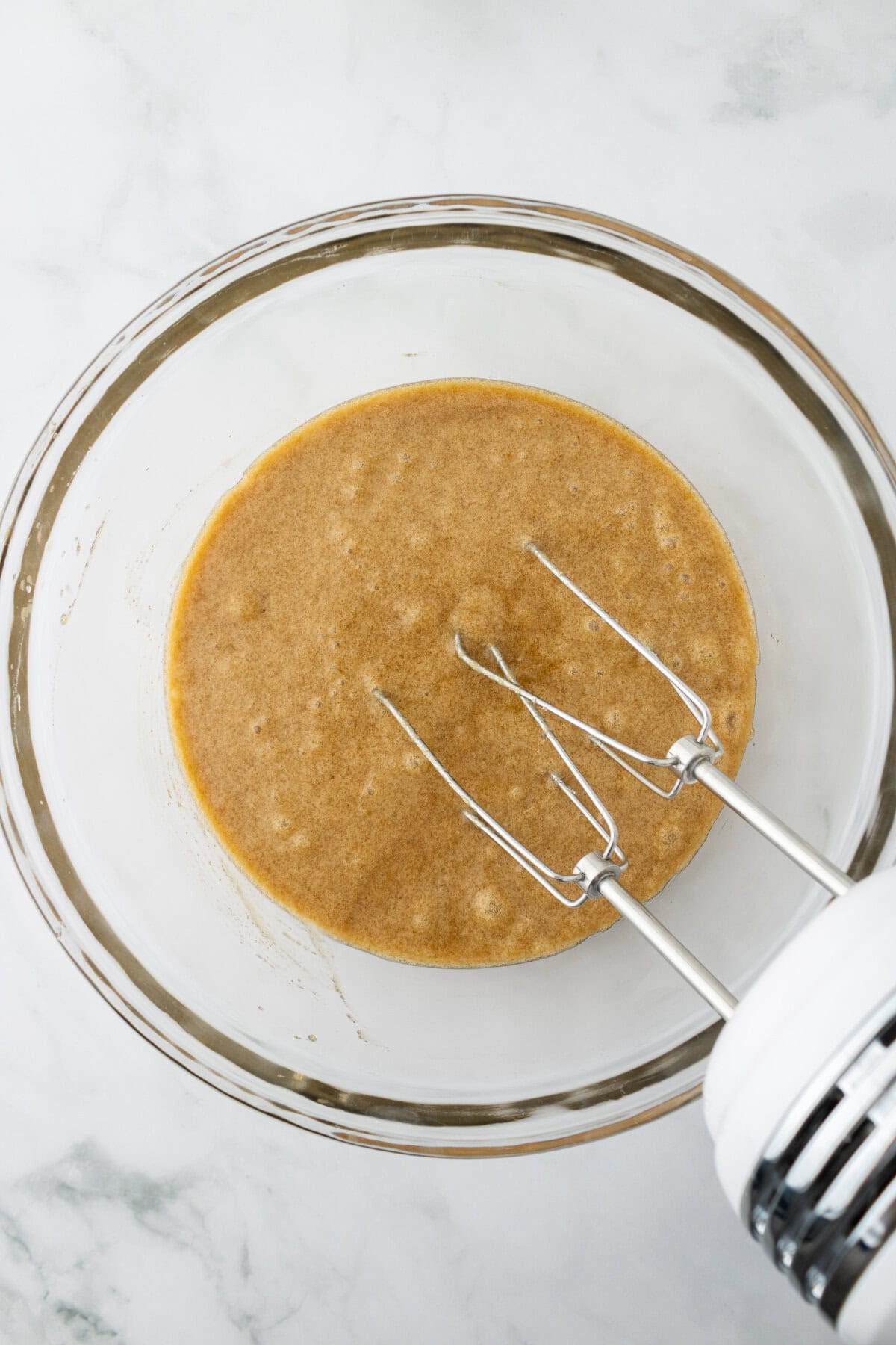 Butter, applesauce, brown sugar, granulated sugar, eggs, and vanilla combined in a glass mixing bowl.