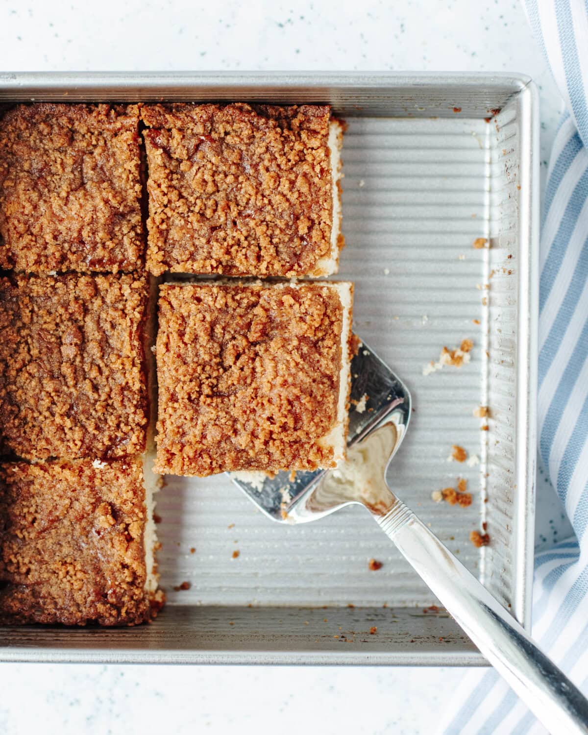 A slice of coffee cake being served from an 8x8 baking pan.