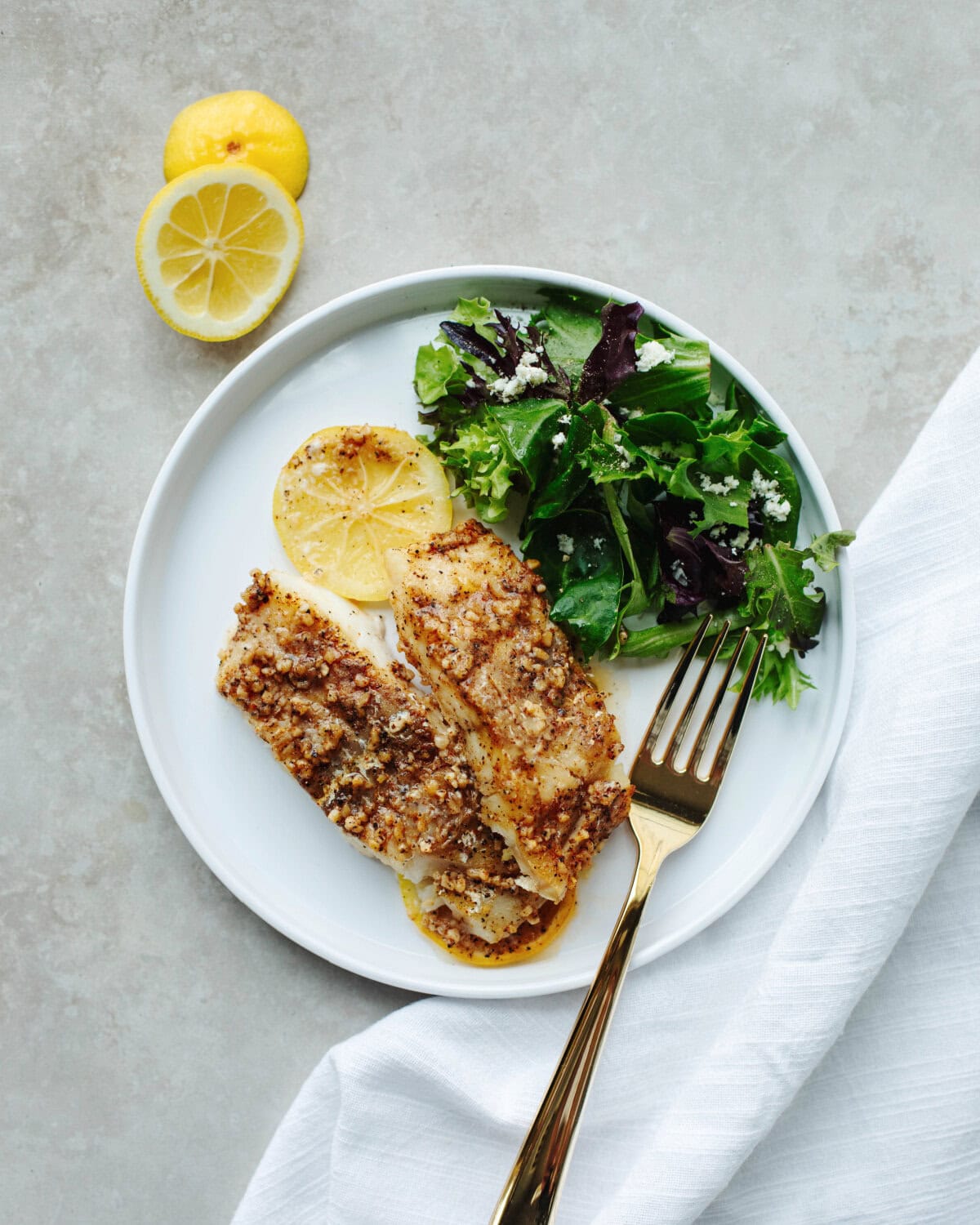 Baked cod filet on a white plate topped with a Cajun sauce.