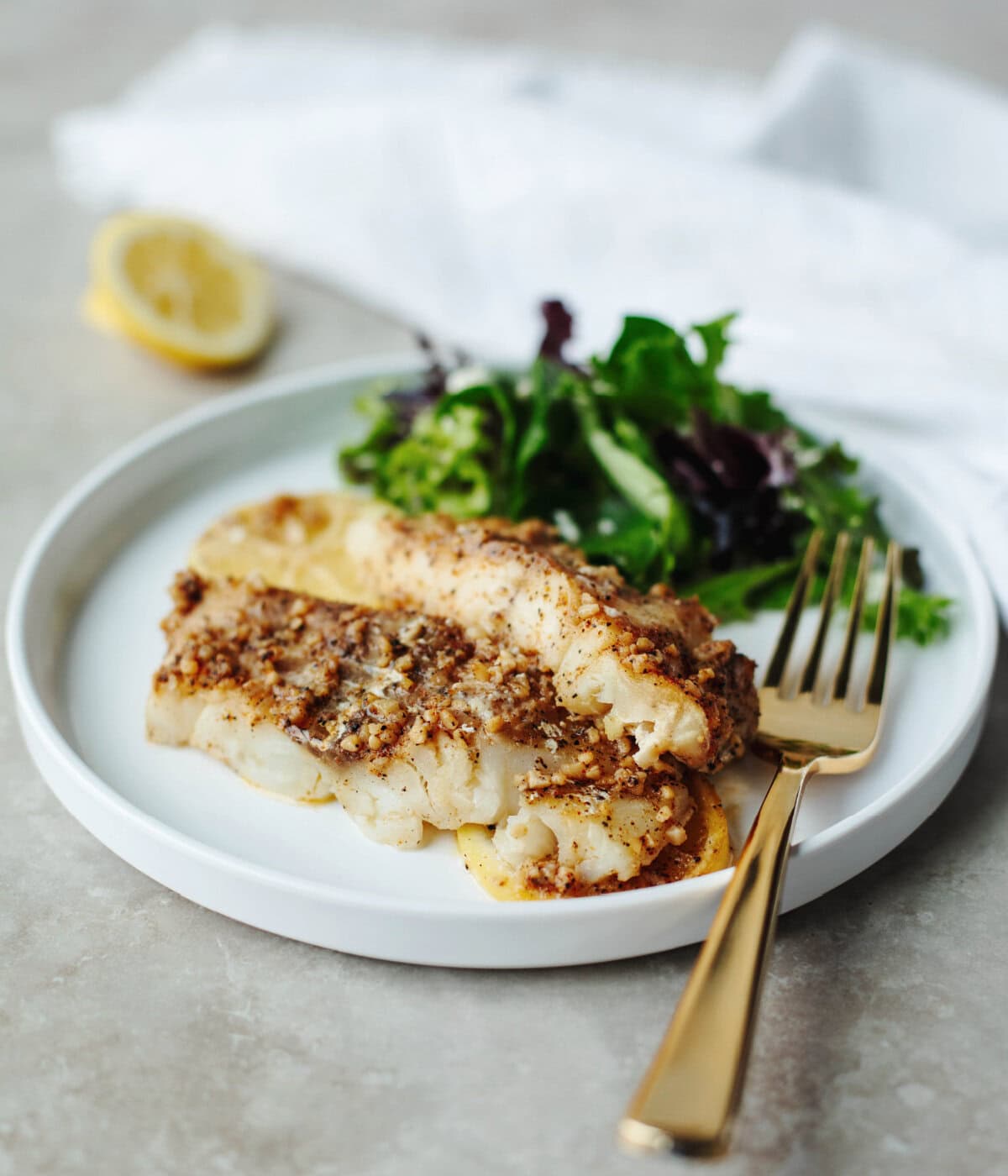 Cajun baked cod served on a white plate with a salad.