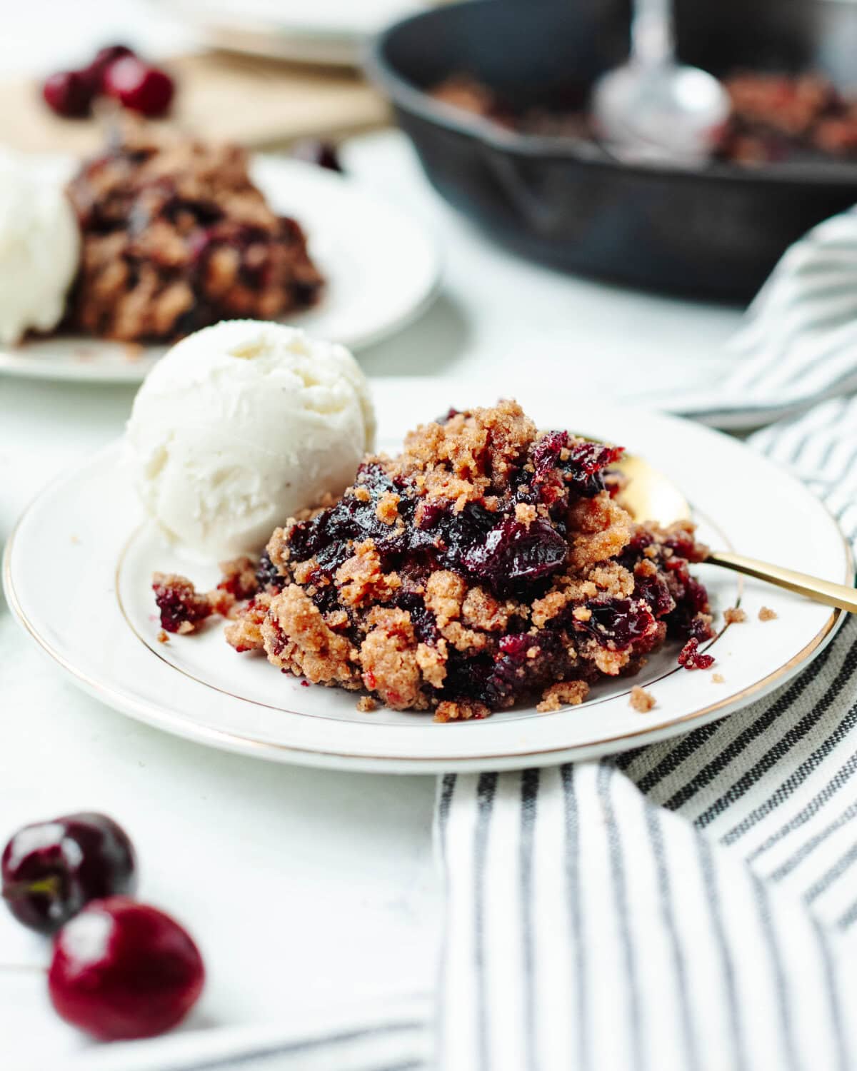 cherry cobbler on a white plate with vanilla ice cream