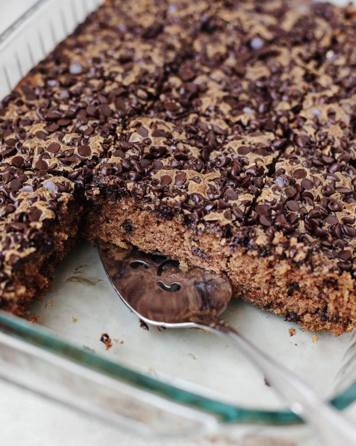 Baked chocolate oatmeal cake in a glass 9x13 baking pan with two slices served.