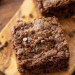 A slice of chocolate oatmeal cake on a wood serving tray.
