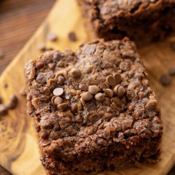 A slice of chocolate oatmeal cake on a wood serving tray.