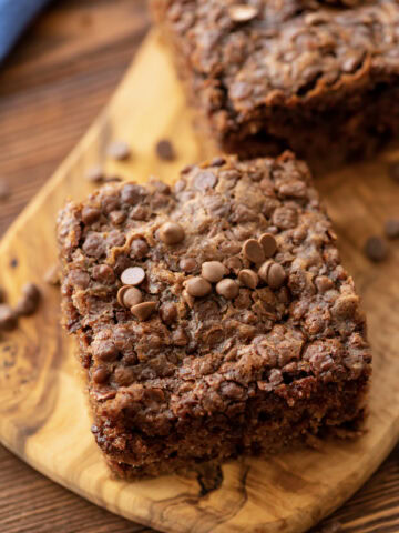 A slice of chocolate oatmeal cake on a wood serving tray.