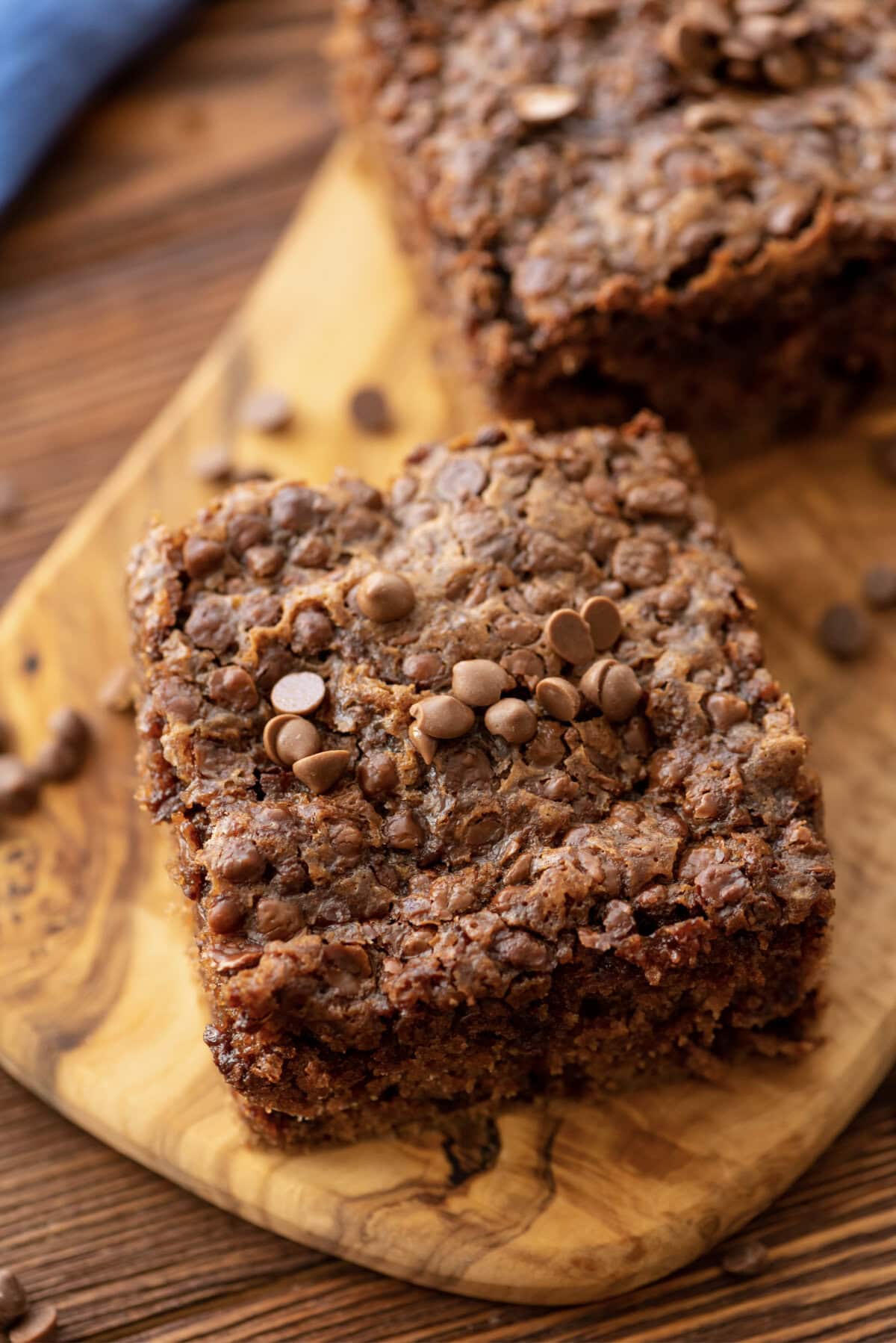 A slice of chocolate oatmeal cake on a wood serving tray.