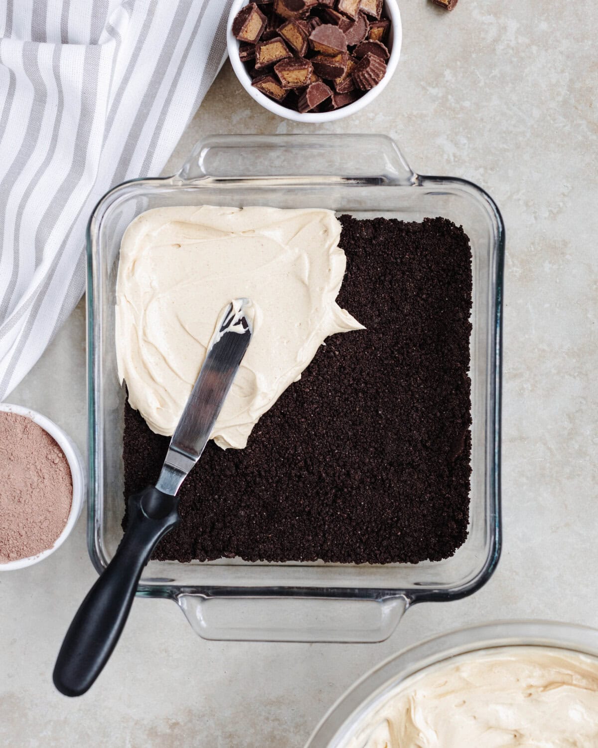 A peanut butter cream cheese mixture spread over Oreo crumbs in a baking dish.