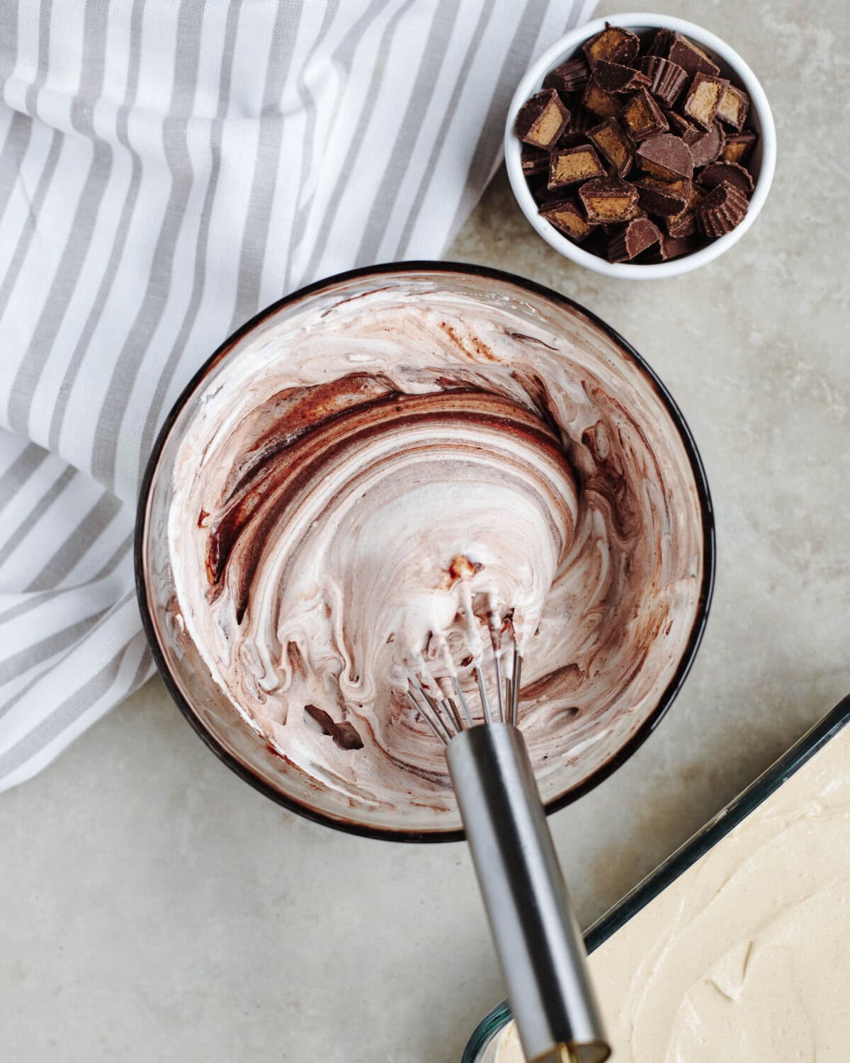 A chocolate pudding whipped cream mixture whisked together in a glass bowl.