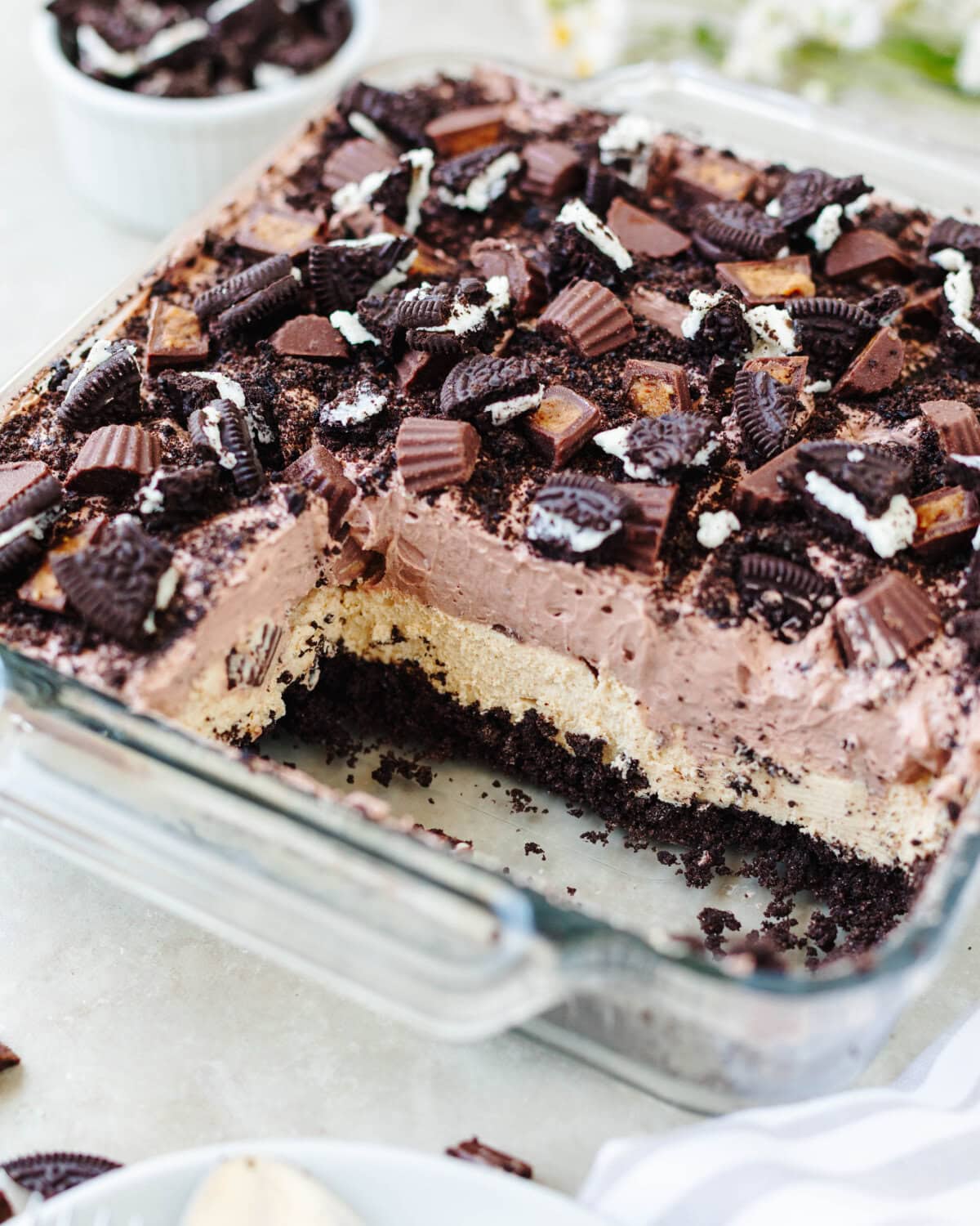 A side view showing the layers of Oreo crumbs, peanut butter cream cheese, instant chocolate pudding mix, and Reese's.